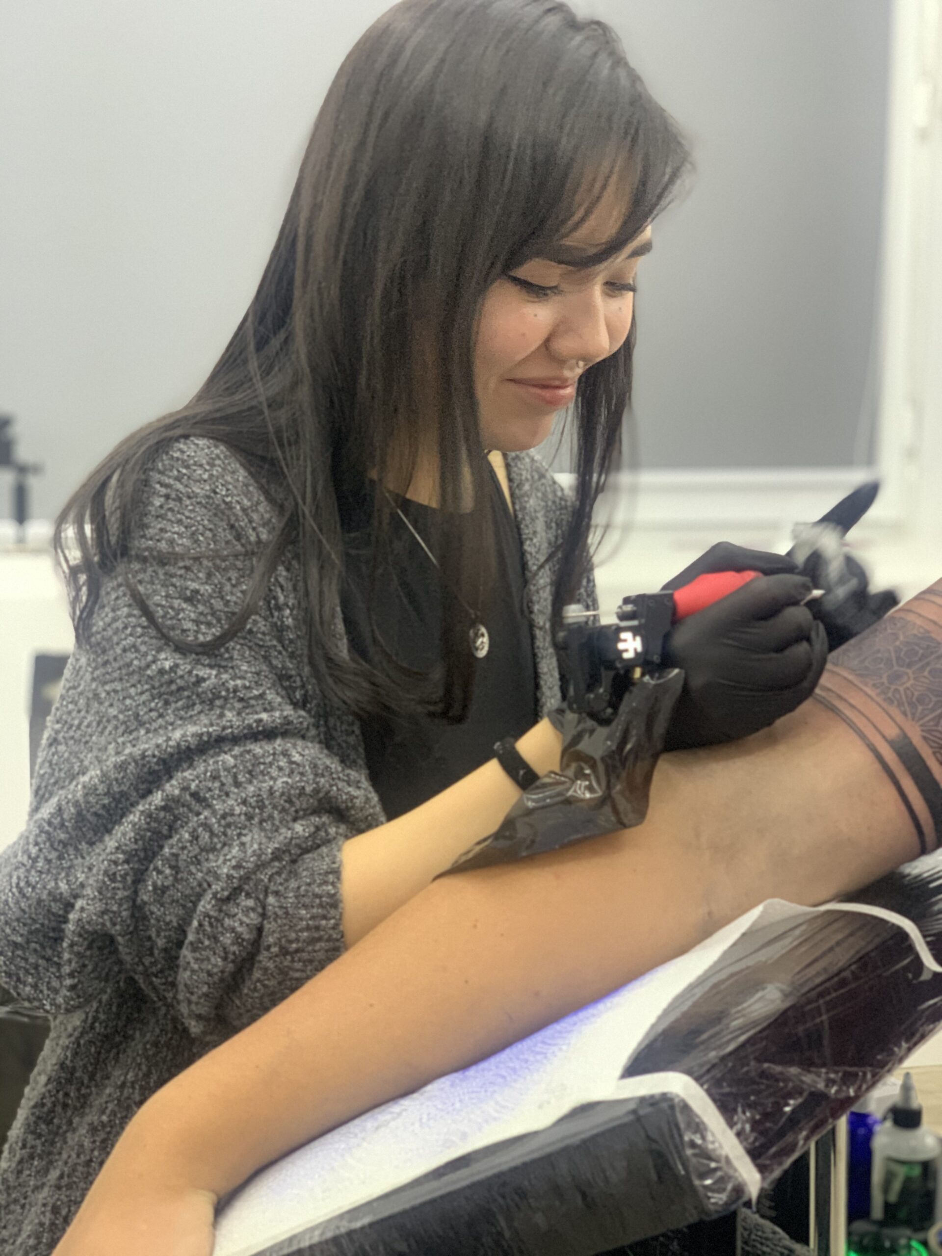 Saltanat Kuanova is in the process of applying a sleeve tattoo to a client scaled